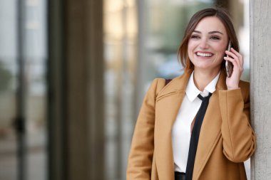 Sarışın, kısa saçlı, beyaz gömlekli, siyah kravatlı ve bej ceketli bir bayan yönetici.