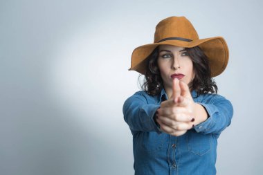 Siyah saçlı, kot gömlekli ve kahverengi şapkalı beyaz bir manken.