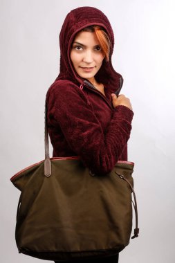 Çantalı güzel kız beyaz arka planda izole edilmiş şekilde eğleniyor.