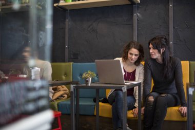 Kafede dizüstü bilgisayarı ve kahvesi olan güzel kadınlar.