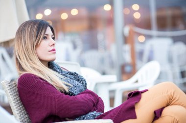 Kumsalda kahverengi süveteri ve boyun atkısı olan güzel esmer kız.