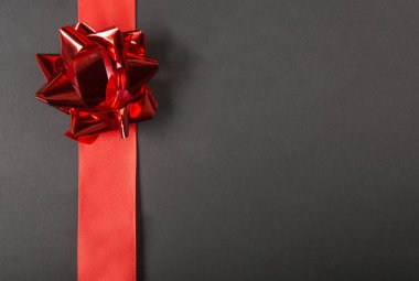 Altın kurdeleli Noel hediyesi kutusu ve siyah arka planda kırmızı kurdele. 