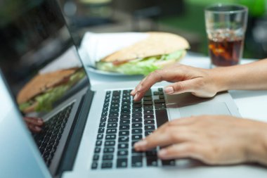 Kafede dizüstü bilgisayarı ve kredi kartı olan bir kadının elleri. 