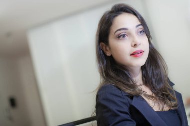 İş yerinde gergin bir ifadeyle oturan esmer bir müdürün portresi.