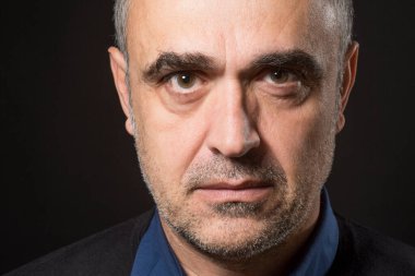 Stüdyoda siyah arka planda poz veren adam
