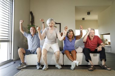 Evde futbol izleyen bir grup mutlu son sınıf öğrencisi.