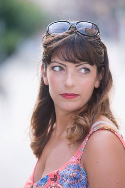 Kafasında güneş gözlüğü olan esmer kadın portresi.