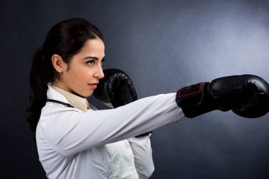 Beyaz önlüklü ve boks eldivenli kadın doktor, beyaz arka planda izole bir şekilde mücadele ve savaşa hazır.