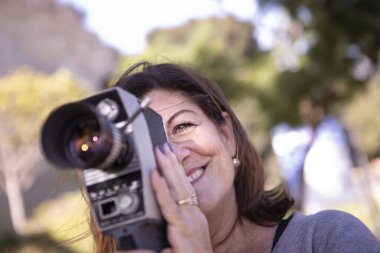 Bayan parkta eski bir analog film kamerasıyla eğleniyor.