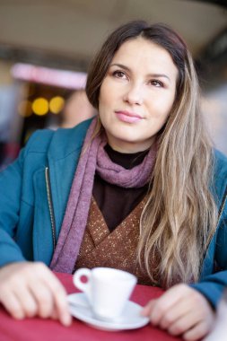 Kafede kahve içen yetişkin bir kadının portresi.