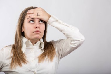 Sarışın kadın elini alnına koyar ve vücut ısısını hisseder. Hafif bir arkaplanda izole edilmiş.