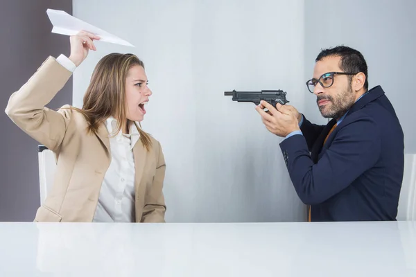 職場に座っている2人の同僚 マネージャーは紙飛行機を起動する驚きの秘書で銃を指します — ストック写真