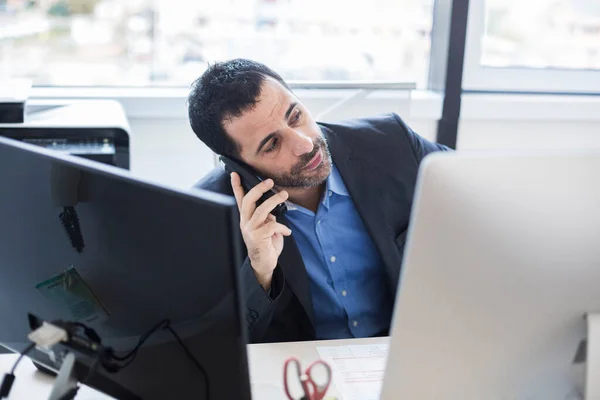 stock image manager dressed in jacket and shirt in his office while talking about work on the phone