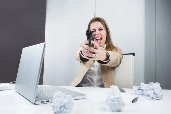 穿着米黄色夹克的金发姑娘正坐在她的工作站前 手里拿着一把准备使用的枪 — 图库照片