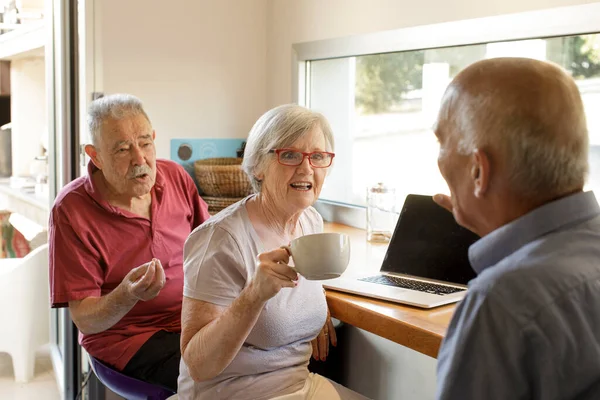 portrait of senior couple drinking coffee and talking while sitting on table
