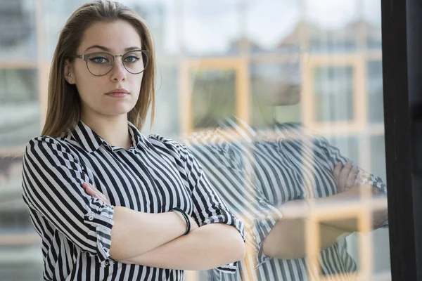 Çizgili Gömlekli Gözlüklü Sarışın Kız Ofisinde Kollarını Kavuşturmuş Dururken Ciddi — Stok fotoğraf