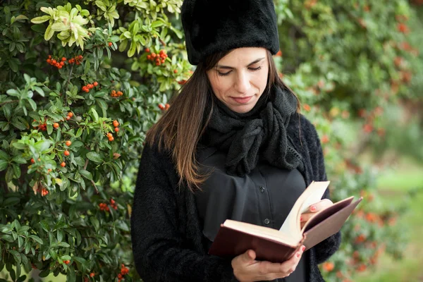 在秋天的公园里 一个年轻美丽的女人在树下看书 — 图库照片