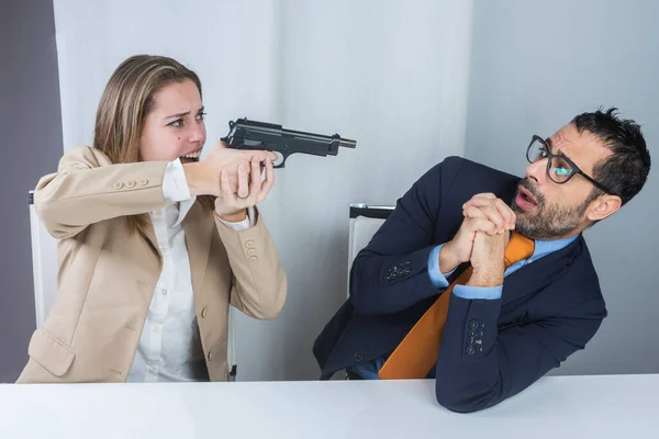 这位无聊的秘书坐在办公室里 两个同事用枪指着她说话的老板 — 图库照片