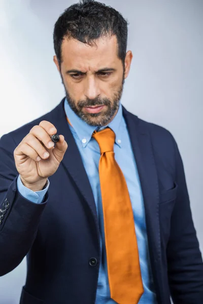 dark-haired man with beard, dressed in shirt suit, orange jacket and tie, draws with a marker on a hypothetical transparent surface, isolated on a white background
