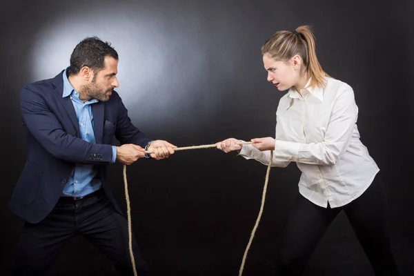 man in jacket does the tug of war against a blonde woman. Each of them strives to win over the other. Isolated on a black background