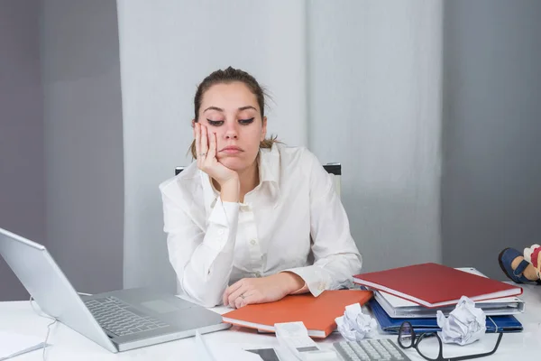 stock image female manager sitting in her desk is depressed about too many commitments