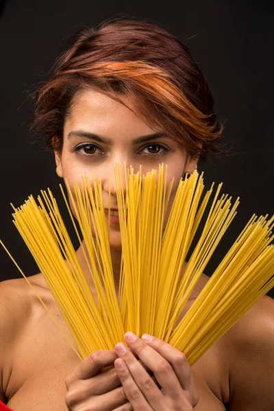 stock image beautiful girl plays showing spaghetti by fanning them, isolated on dark background