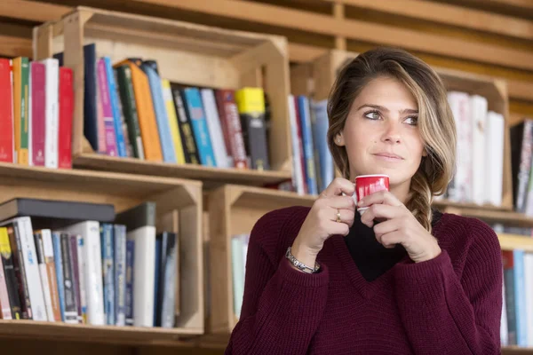 一个在图书馆喝咖啡的年轻女人 — 图库照片
