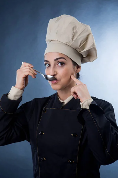 スプーンで料理を味わう料理人女性灰色の背景に隔離された — ストック写真