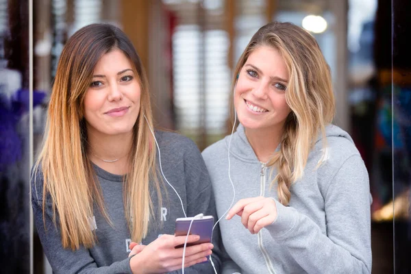 Portret Dwóch Młodych Kobiet Słuchających Muzyki Wraz Przewodowymi Słuchawkami Smartfonem — Zdjęcie stockowe
