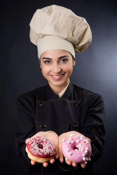 Cozinheiro Sorridente Mostra Bem Donuts Coloridos Isolados Fundo Preto — Fotografia de Stock