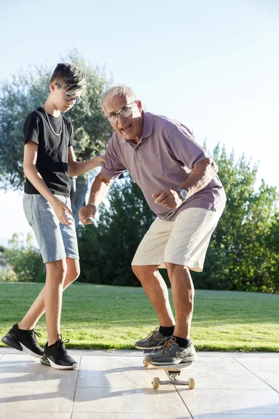 Teenage Grandson Teaches His Elder Grandfather Skateboard Garden — Stock Photo, Image