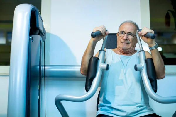上了年纪的人在健身房的机器上训练 — 图库照片