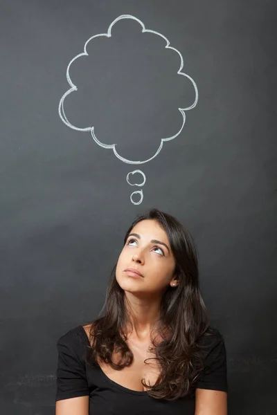 stock image Dark-haired girl makes a funny face with a speech bubble drawn in the background that simulates thoughts