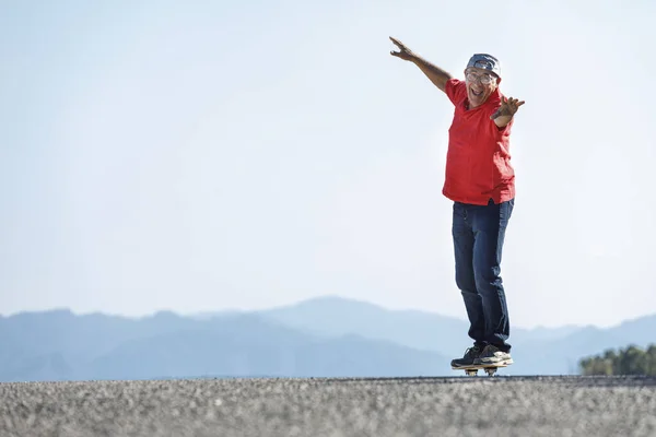 Senior Jersey Rojo Disfruta Del Skateboarding Una Carretera Rural — Foto de Stock
