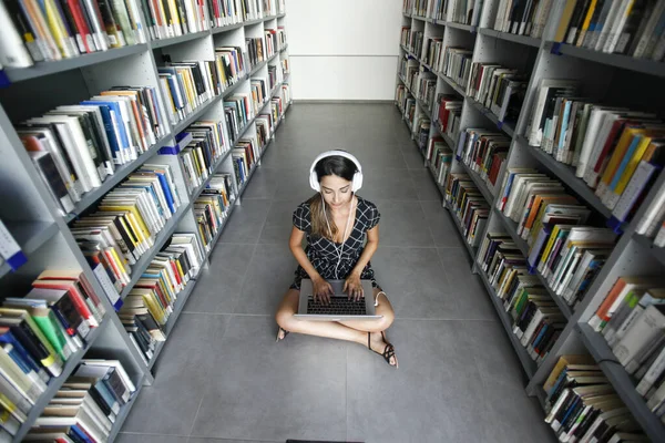 Genç Kız Kütüphanede Kulaklıkla Müzik Dinliyor — Stok fotoğraf