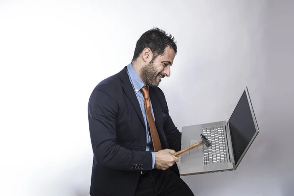 黑发男子留着胡子 身穿衬衫套装 夹克和橙色领带 手里拿着一个带锤子的笔记本电脑 与白色背景隔离 — 图库照片