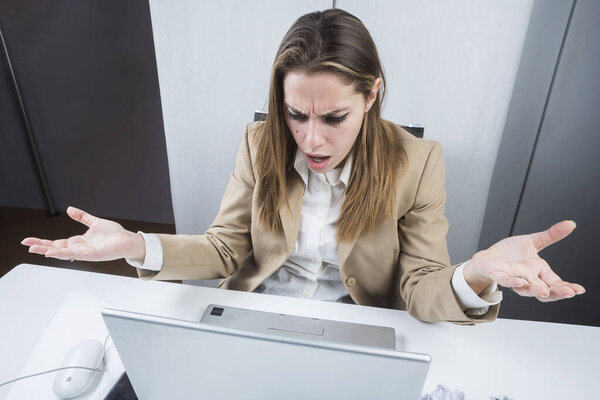 Менеджер, одетый в пиджак и рубашку, сидит за столом и с изумлением смотрит на компьютер