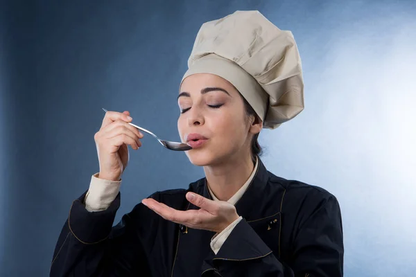Mujer Chef Prueba Plato Una Cuchara Aislado Sobre Fondo Gris — Foto de Stock