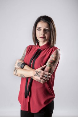 Gri arkaplanda dövmeleri olan güzel bir genç kadının portresi.