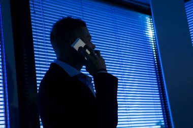 Cagliari, İtalya - 03-20-2018: Ceket ve gömlek giymiş sarışın beyaz adam ofisinde cep telefonu görüşmesi yapıyor 