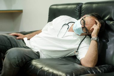 50 yaşında, beyaz önlüklü bir doktor.