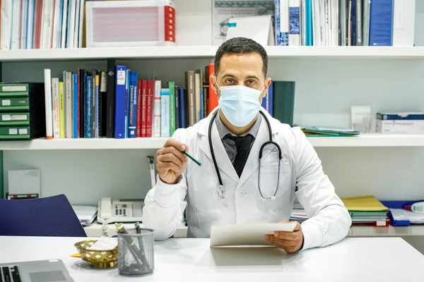 Médico Cabelos Pretos Com Casaco Branco Dados Sentados Mesa Seu — Fotografia de Stock