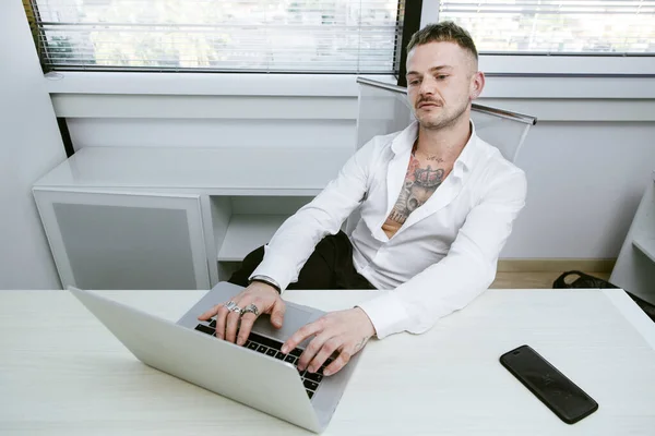 カリアリ イタリア 2018 白いシャツとタトゥーのある白いマネージャーは 彼のオフィスのコンピュータの前の机の上に座っている彼の体のすべての作品 — ストック写真