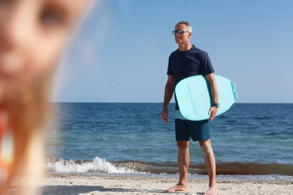 ビーチでサーフボードを持つ男は距離を調べる — ストック写真