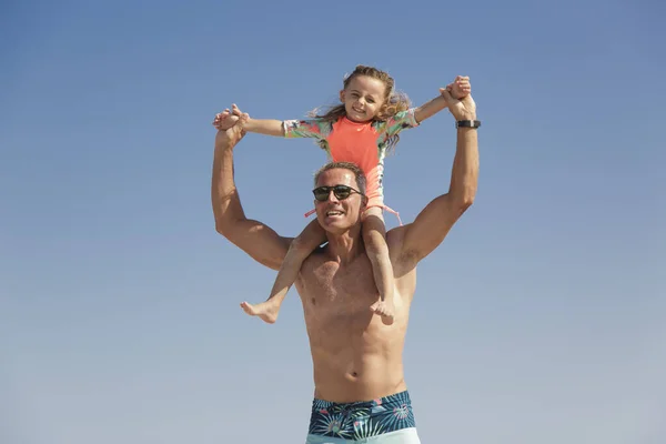 一位父亲把女儿抱在肩上 在海滩上与她好好地玩耍 — 图库照片