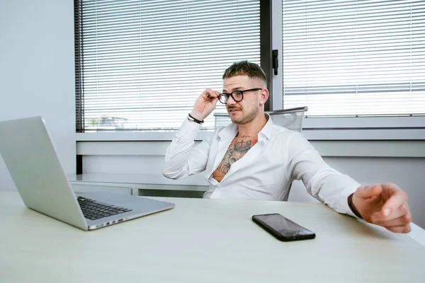 意大利卡利亚里 身穿白衬衫 全身都是纹身的白衣经理坐在办公室电脑前的桌子上 — 图库照片