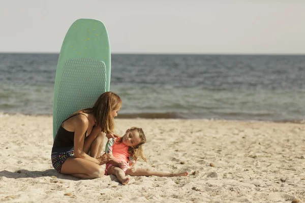 穿着泳衣的妈妈和她的女儿在海边玩得很开心 — 图库照片