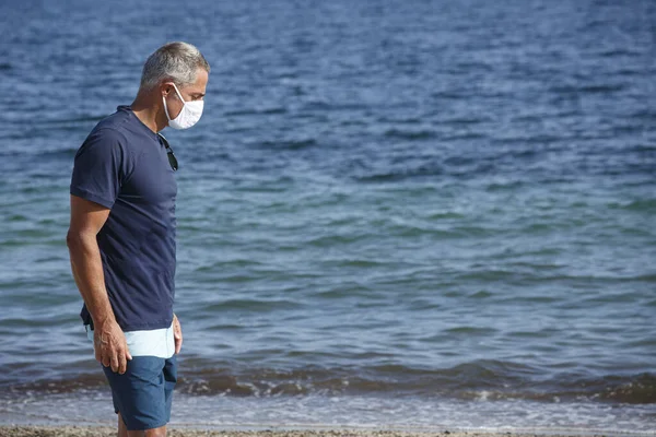Homem Anos Idade Com Máscara Protetora Fica Praia Parece Desolado — Fotografia de Stock