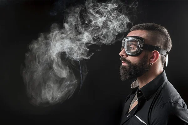 stock image portrait of smoking handsome bearded man with tattoos on dark background