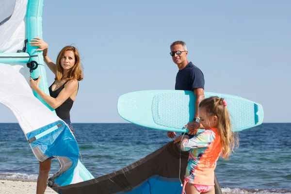 由父亲 母亲和女儿组成的家庭准备在海滩上冲浪 准备在海上使用 — 图库照片